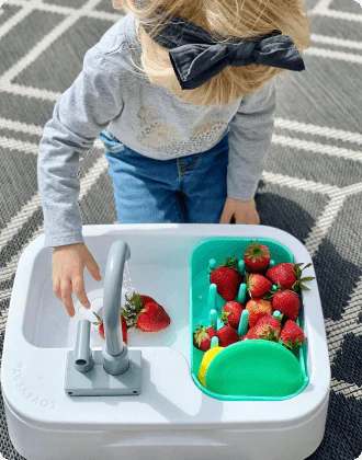 Child washing strawberries in the Super Sustainable Sink from The Helper Play Kit